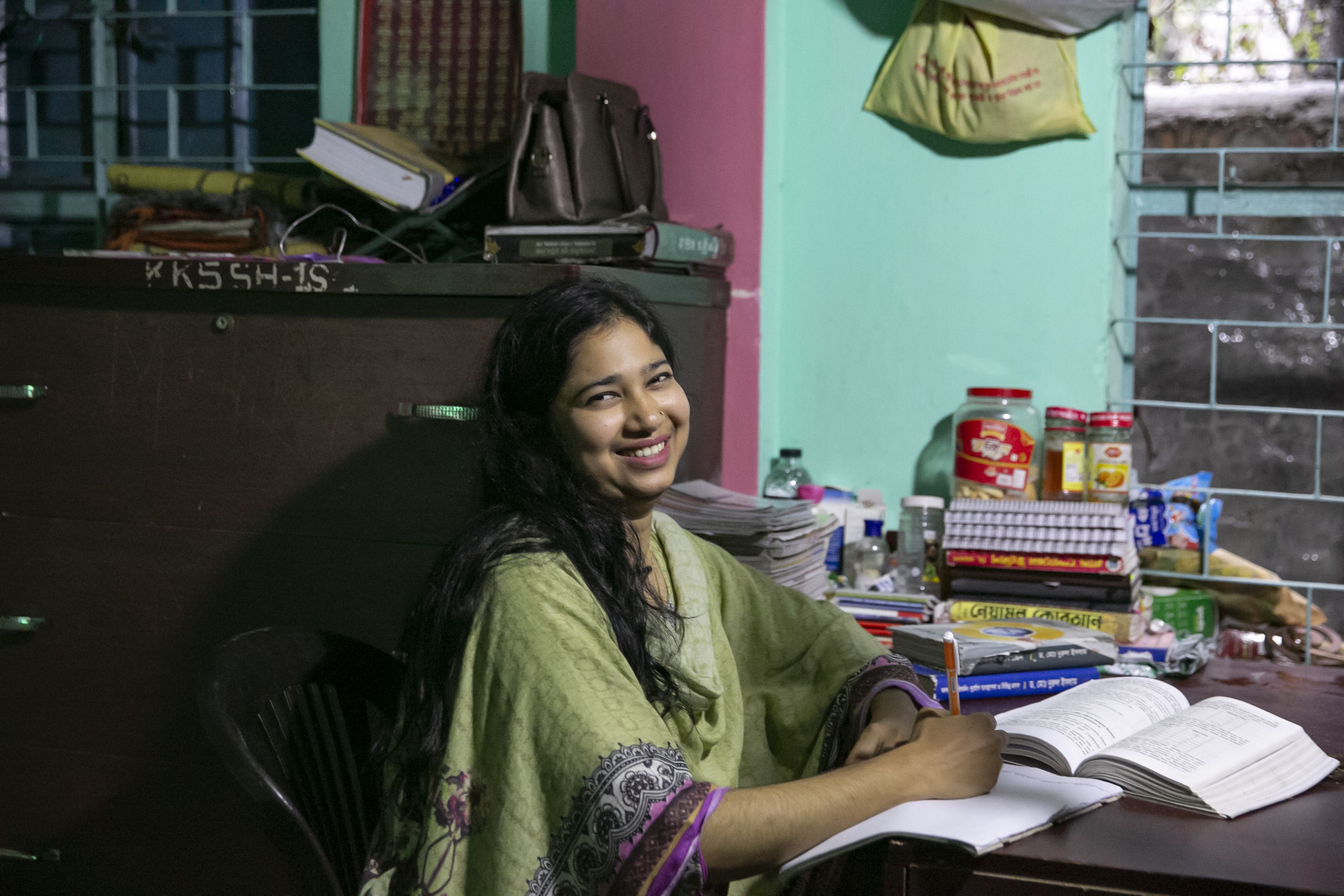Bobita*, 24, smiles at her desk at the Save the Children run safe house where she now works as a Mentor in Rajbari District Bangladesh