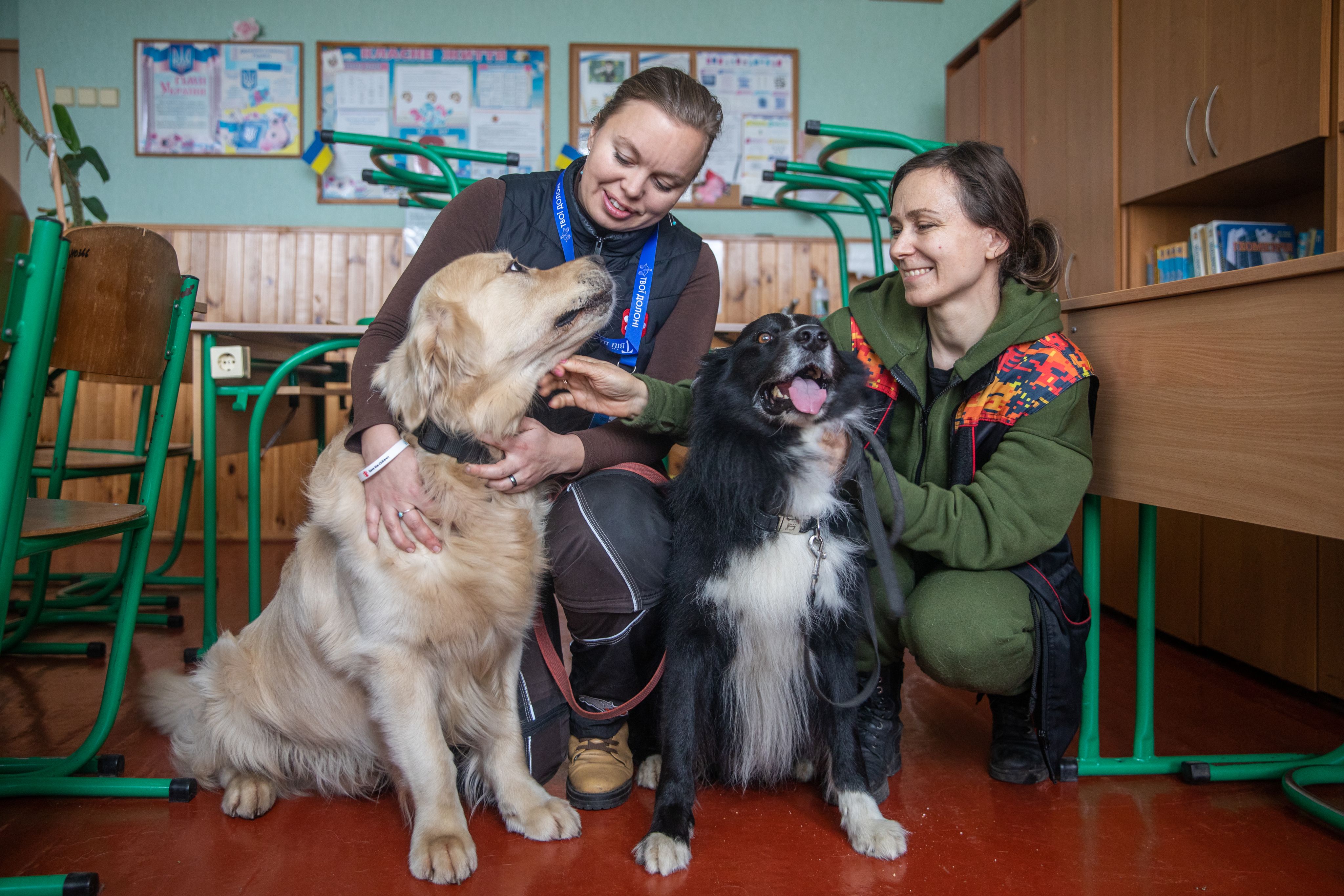Nataliya (left) and Olena (right), canine therapy specialists, with therapy dogs golden retriever Parker and border collie Best at a school outside of Kyiv, Ukraine.