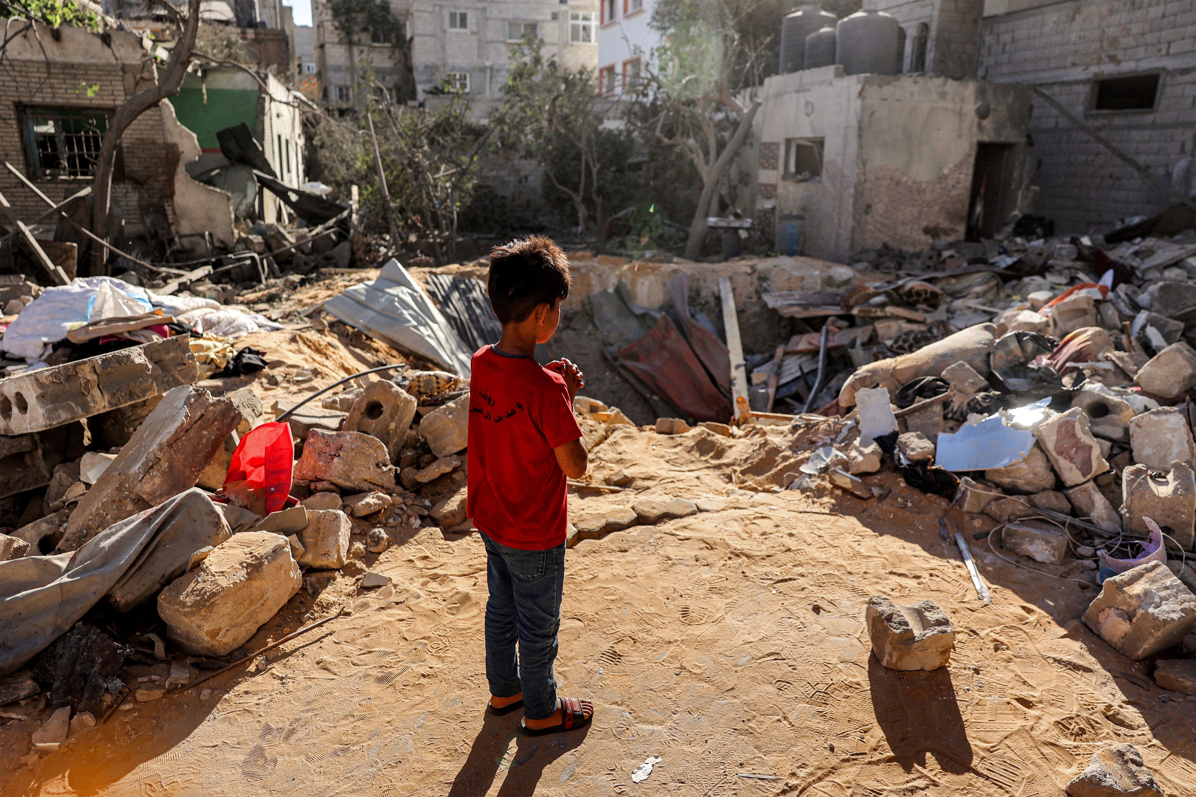 A boy stands before an impact crater at the site of a building that was hit by Israel bombardment in Rafah, Gaza.