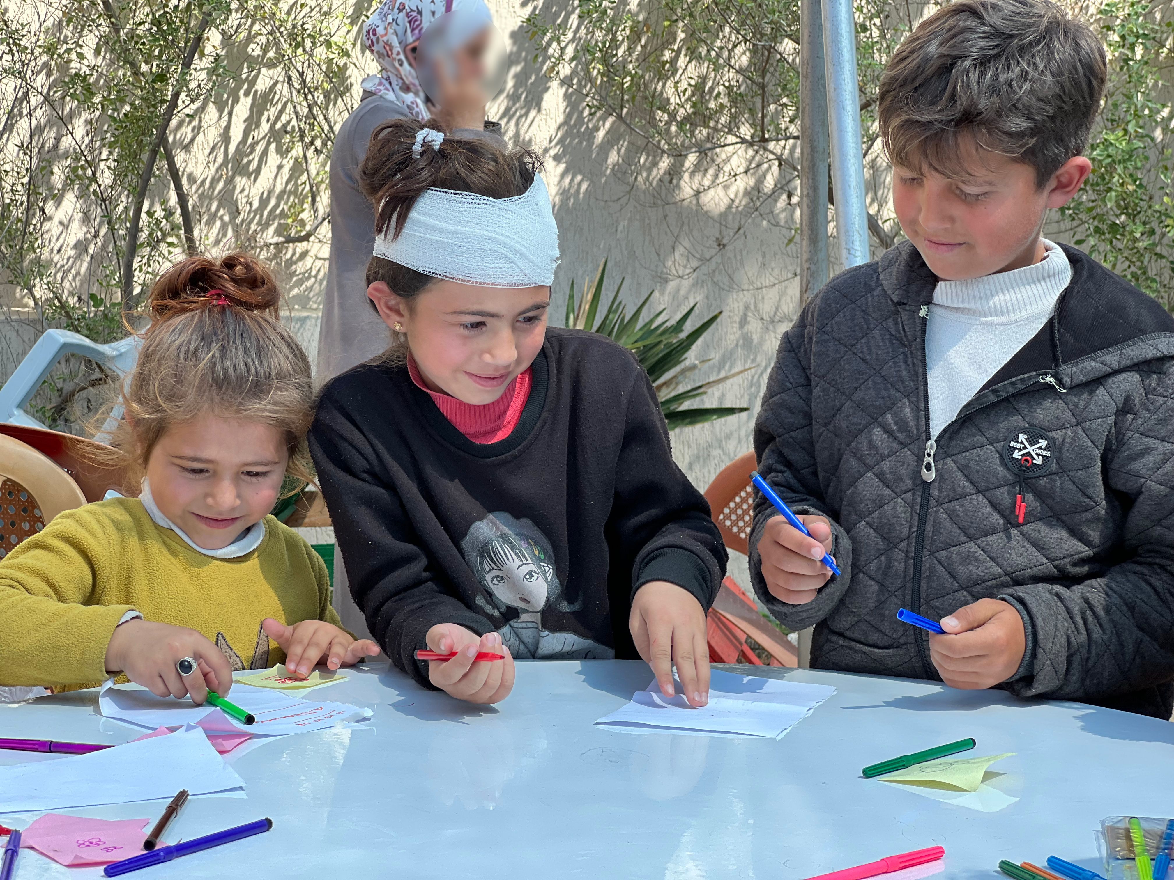 Dalia*, 9, with her siblings Eyad*, 12, and Noha*, 6, at a Save the Children Temporary Learning Space in Gaza.