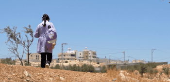 Mona*, 12, walks to school with her school bag on her back
