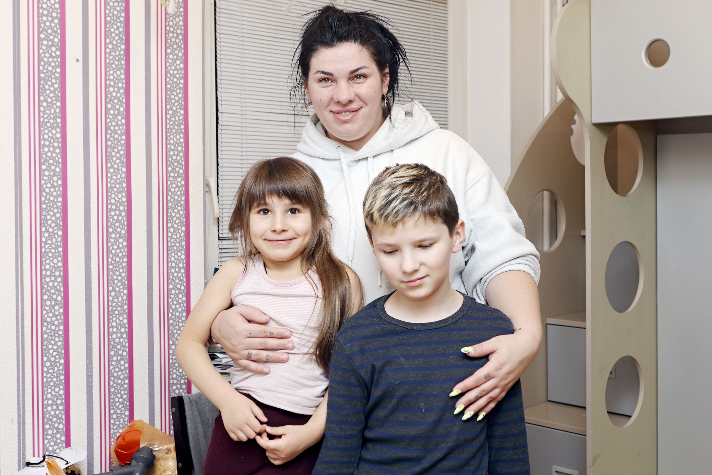 Oksana*, 39, hugging her children Polina*, 5 and Matvii*, 10, Lithuania