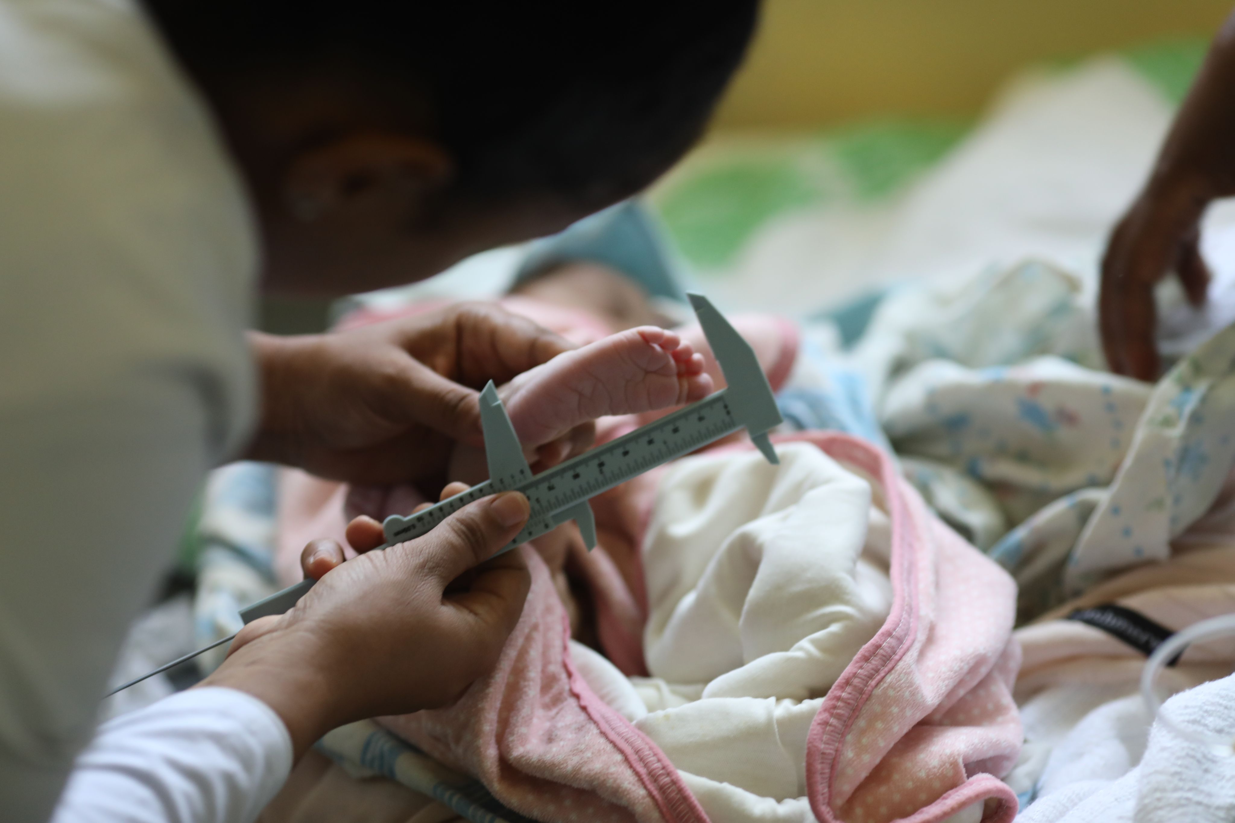   A health worker measuring newborn foot length