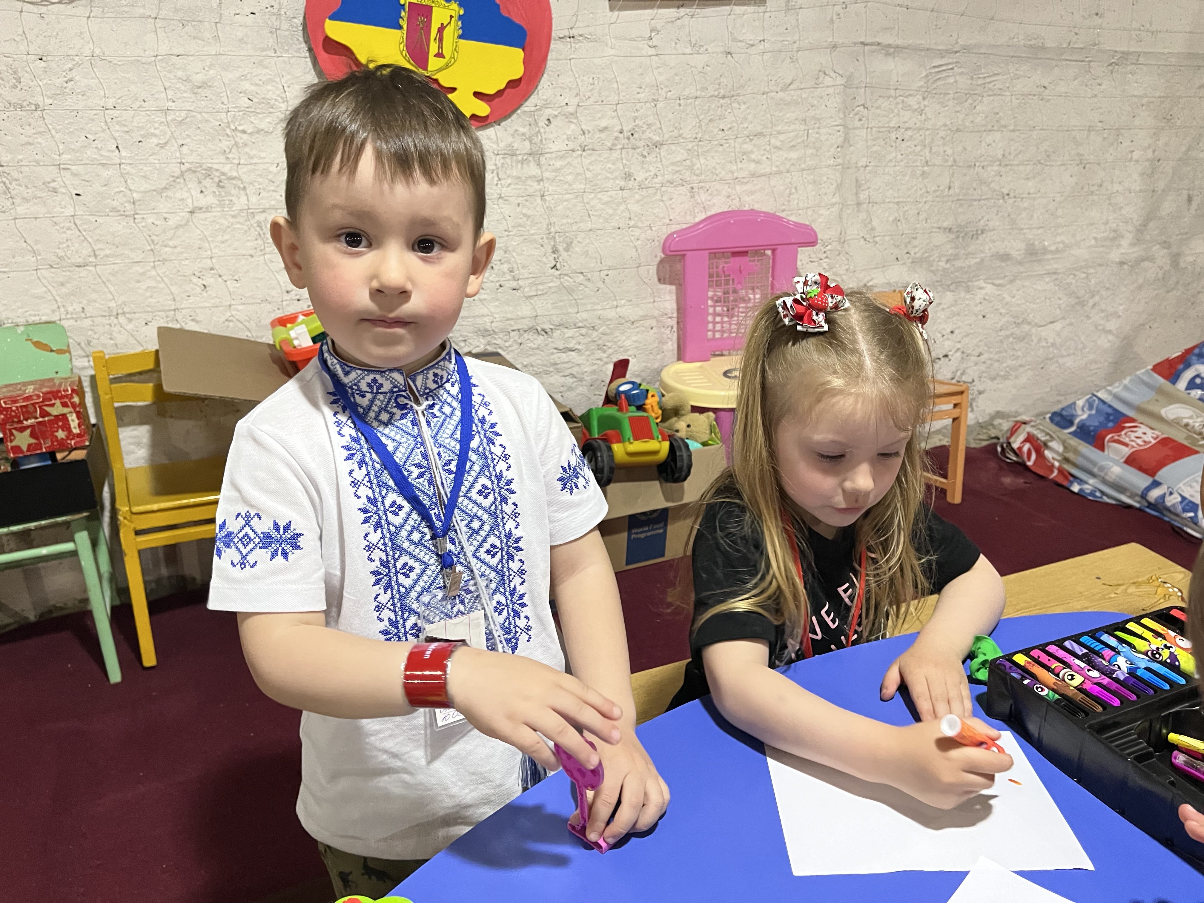Oleh*(4) and Olena*(4) draw in the bomb shelter of their kindergarten during air alarm in Dnipro, Ukraine.