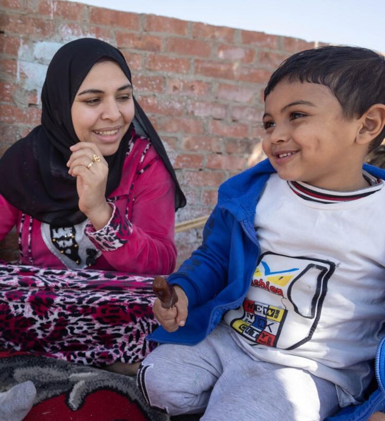 Photo: Iman, in a pink top and black headscarf, plays with her children Hassan, 4, and Hoor on the rooftop of their home, Egypt. Credit: Sima Diab/Save the Children.