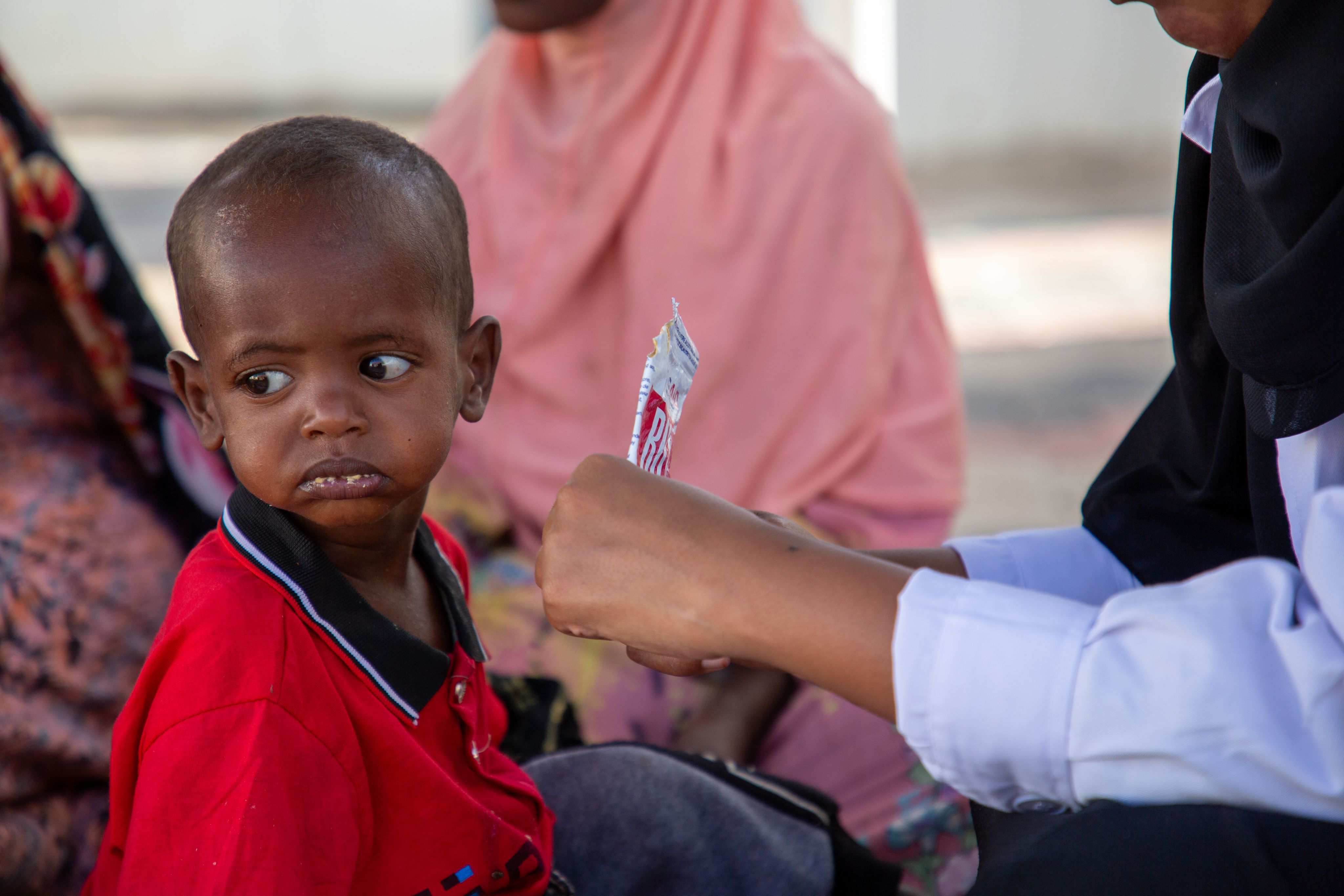 A Save the Children nurse provides Abdi* 17 months, with a nutritional sachet to combat malnutrition, Somaliland