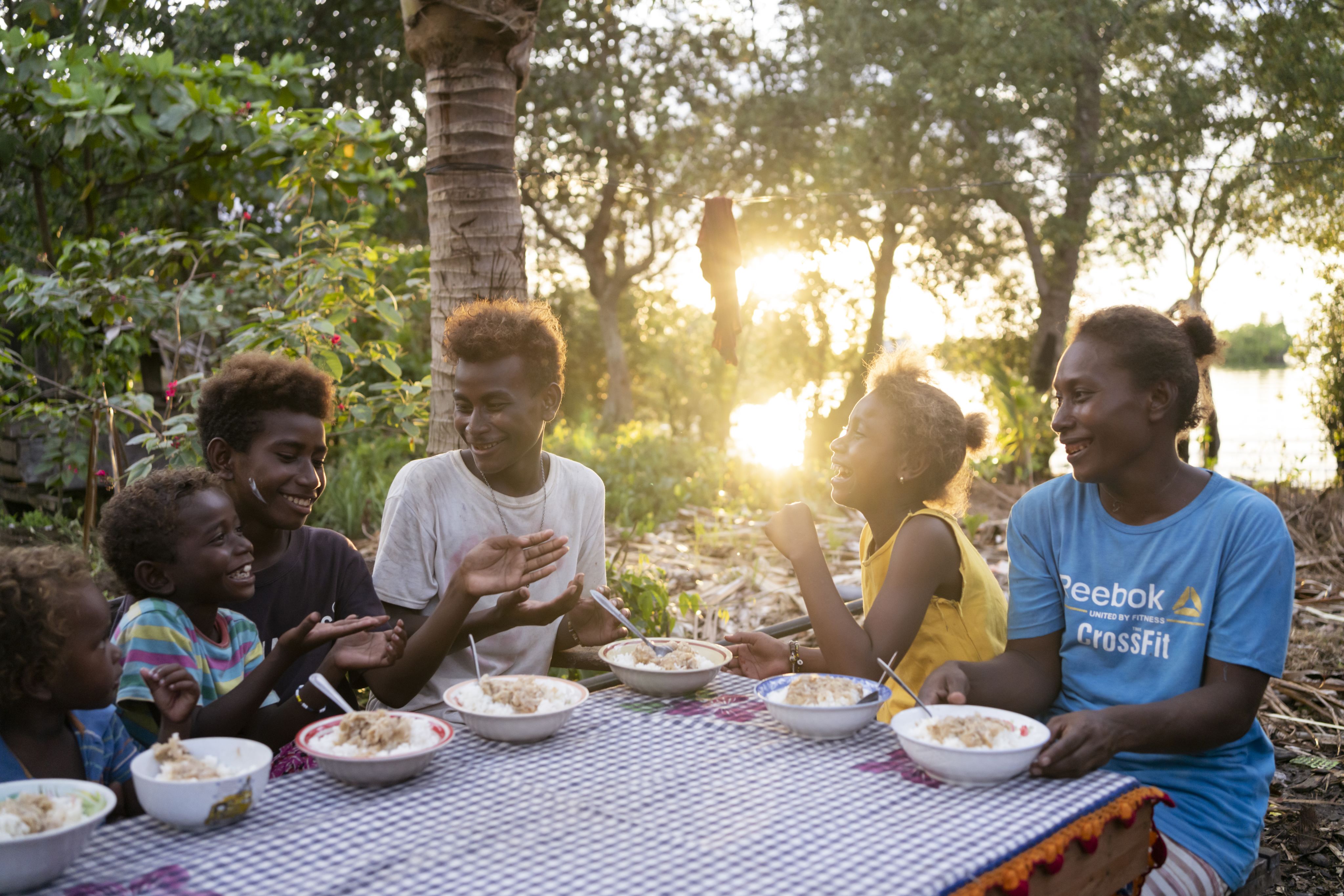 unior, 16, and his family eating dinner together outside their home in a community affected by rising sea levels in Malaita Province, the Solomon Islands.