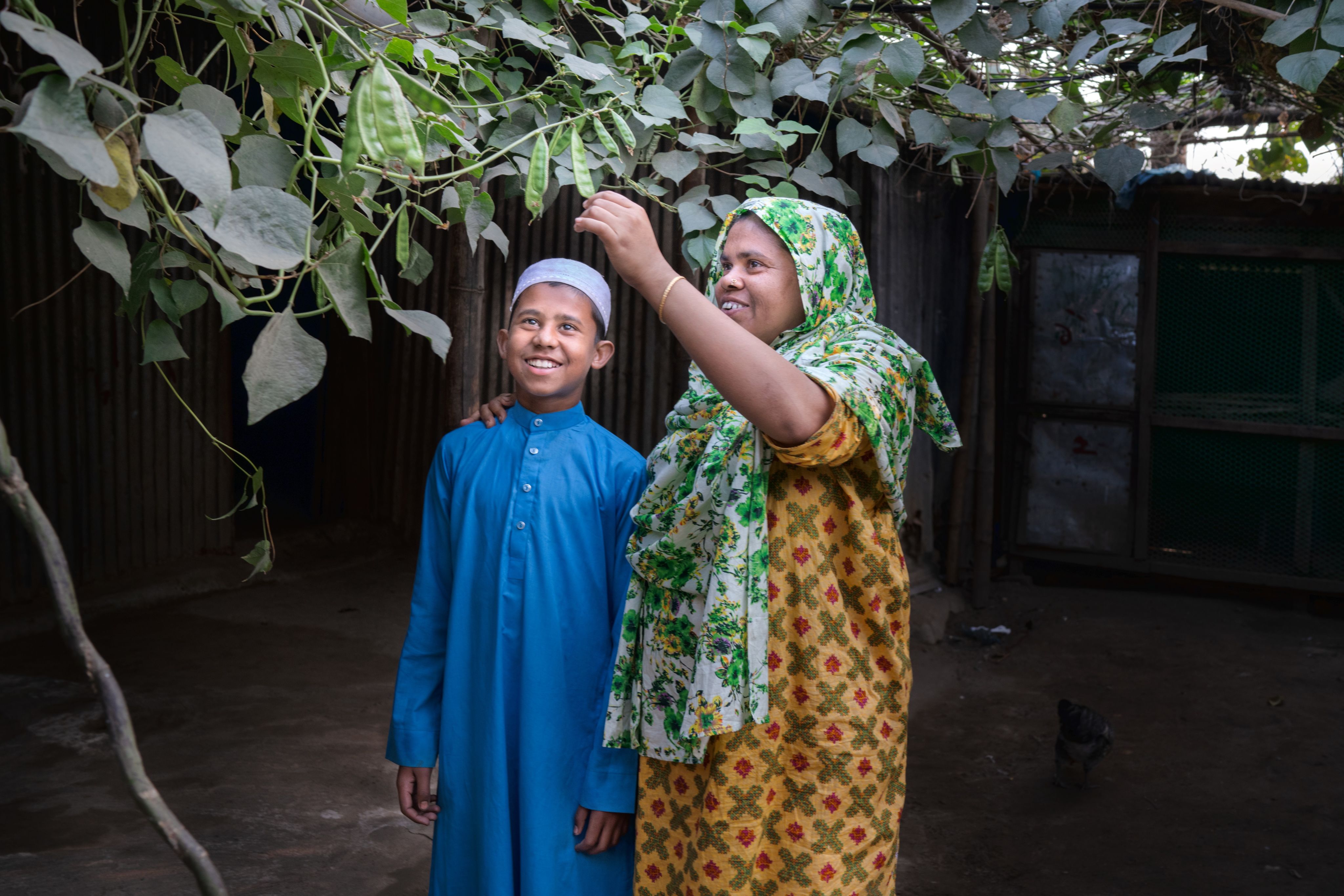 Junaed, 10, smiles as his mother shows him one of the plants in her model farm at home in Sylhet, Bangladesh. 