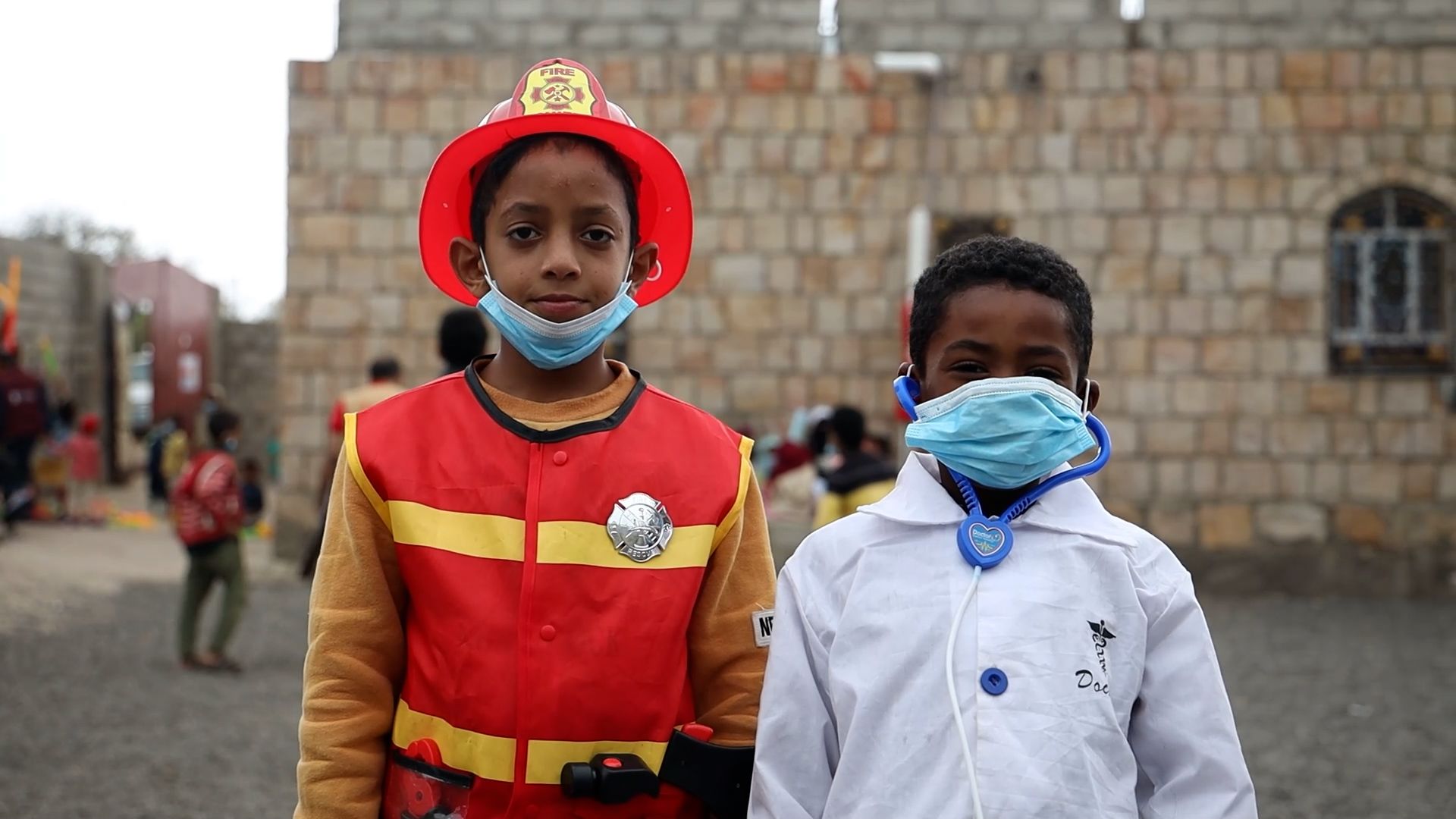 Two children dressed as a firefighter and a doctor at a social centre in Yemen
