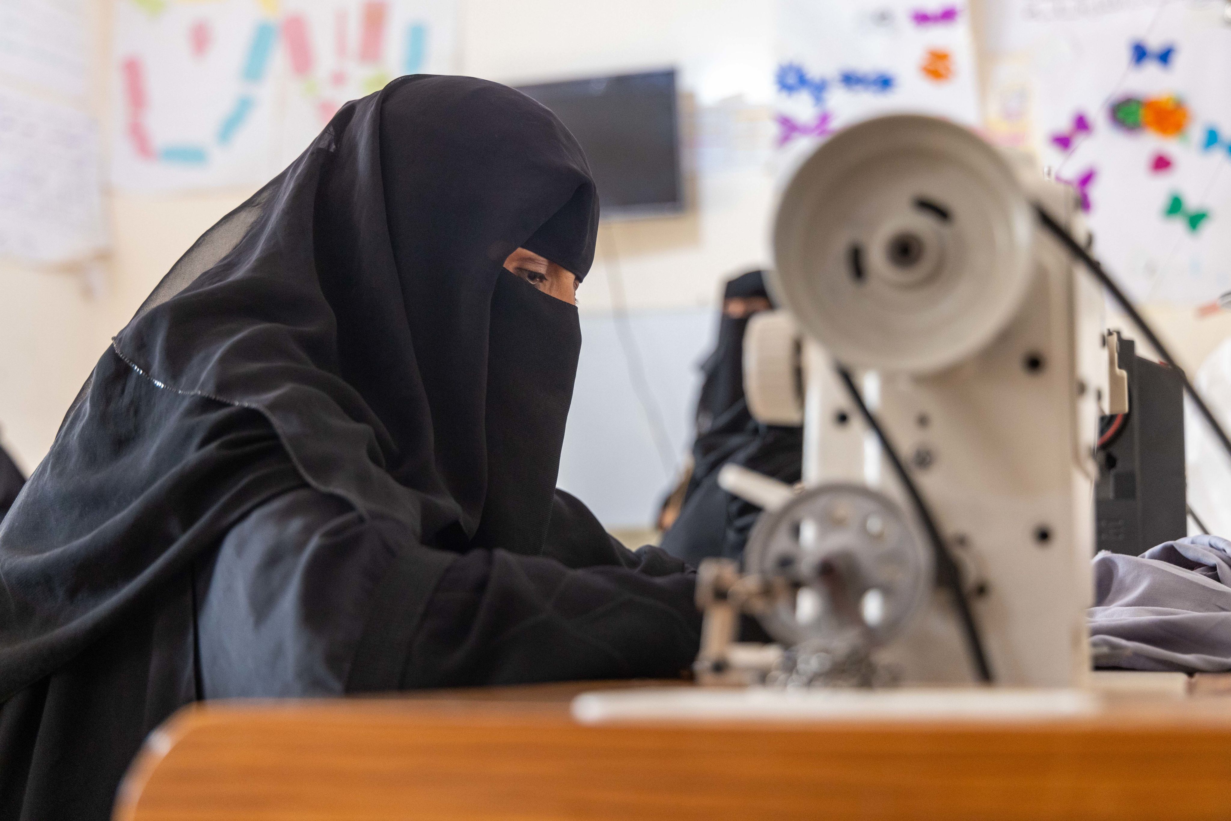 A woman in Yemen uses a sewing machine at a Save the Children supported community centre