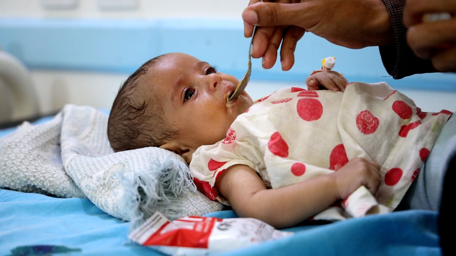 A six month old baby is spoon fed by her mother at a health centre in Yemen