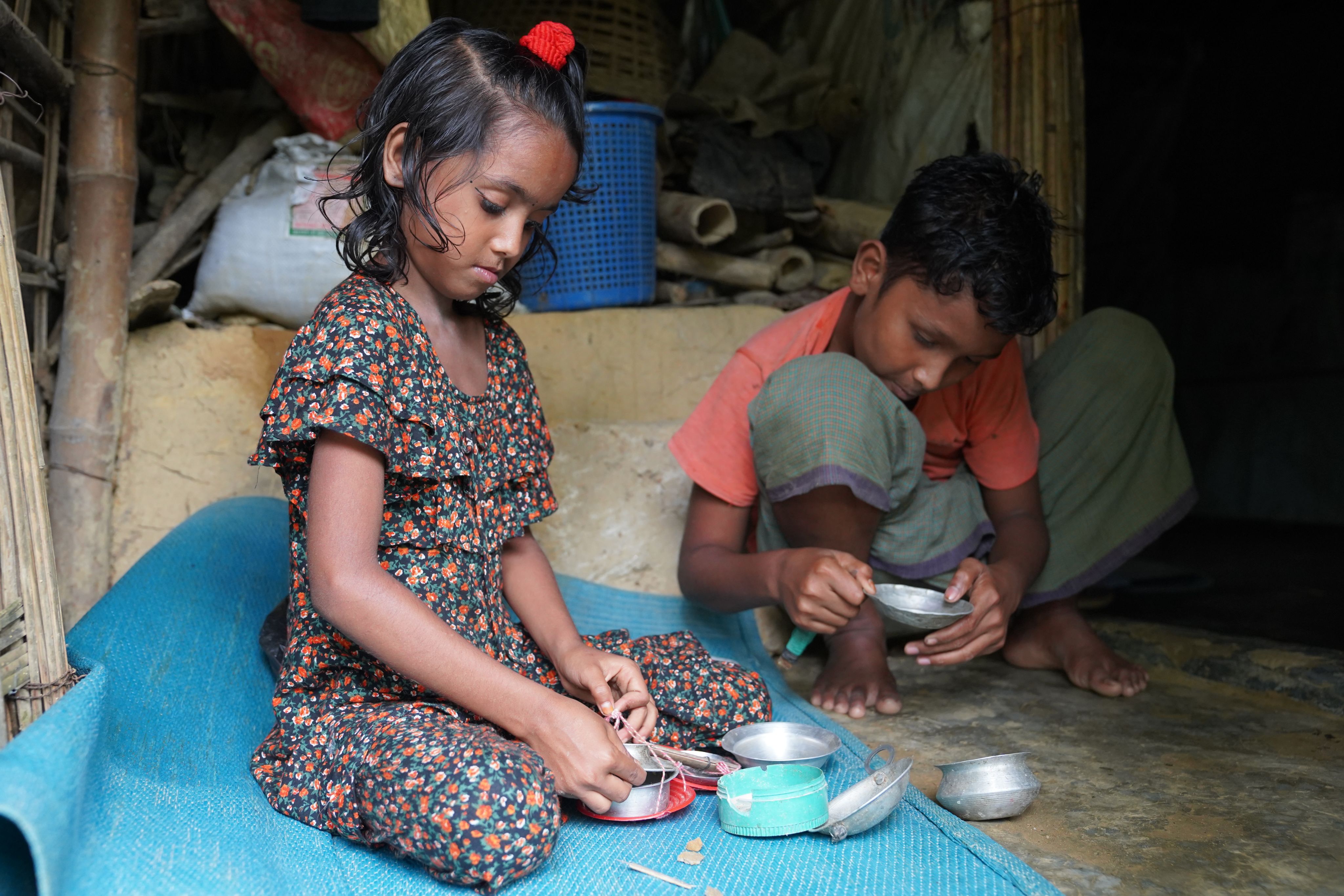 Sultana*, 7, and Rakib*, 12, play with small spice containers in their family's kitchen in Cox's Bazar, Bangladesh.