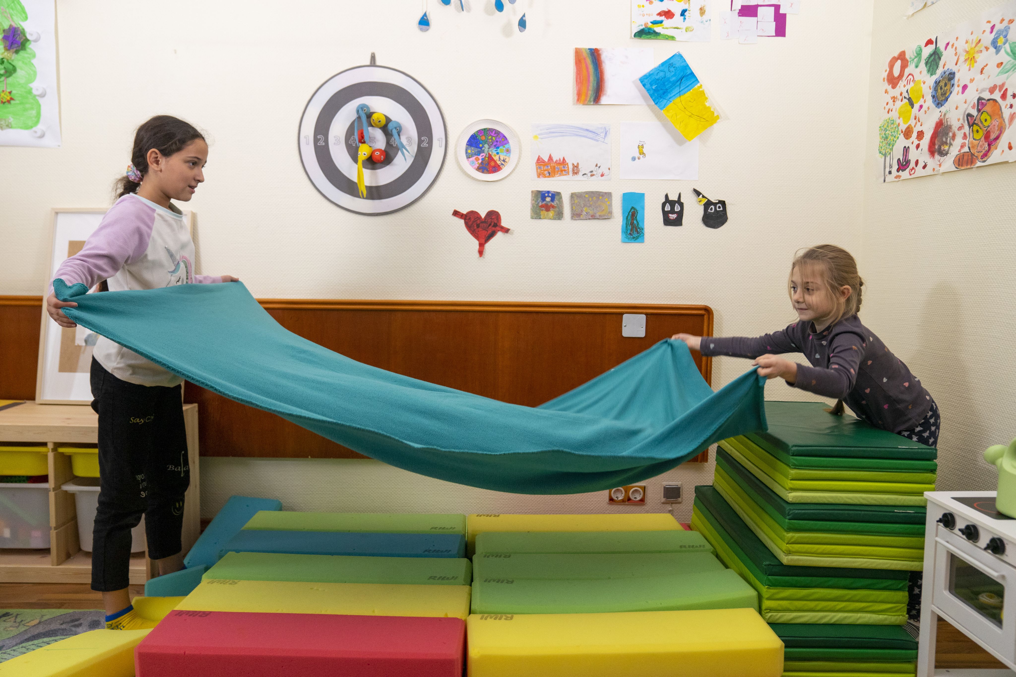 Daniela*, 11 and Larissa*, 7 extend a blanket in the Child Friendly Space