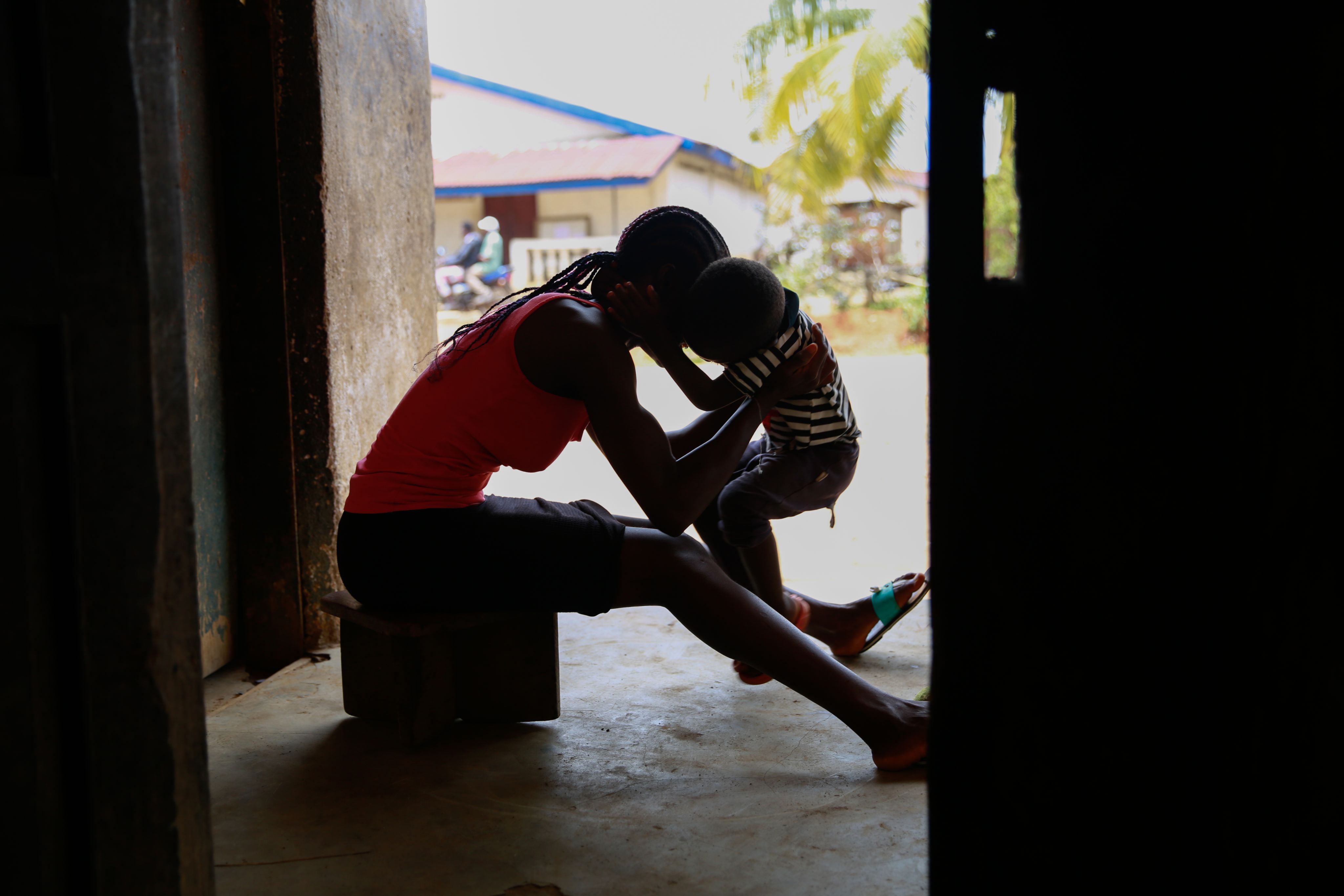 Kuji*, 19, plays with her 3 year old son at home in Kailahun, Sierra Leone