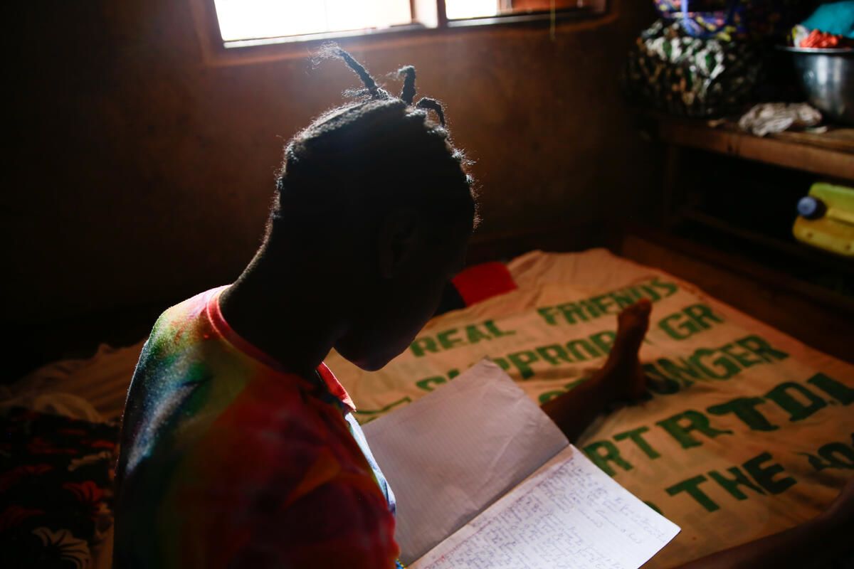 Kpemeh*, 18, studying on her bed at home in Kailahun, Sierra Leone