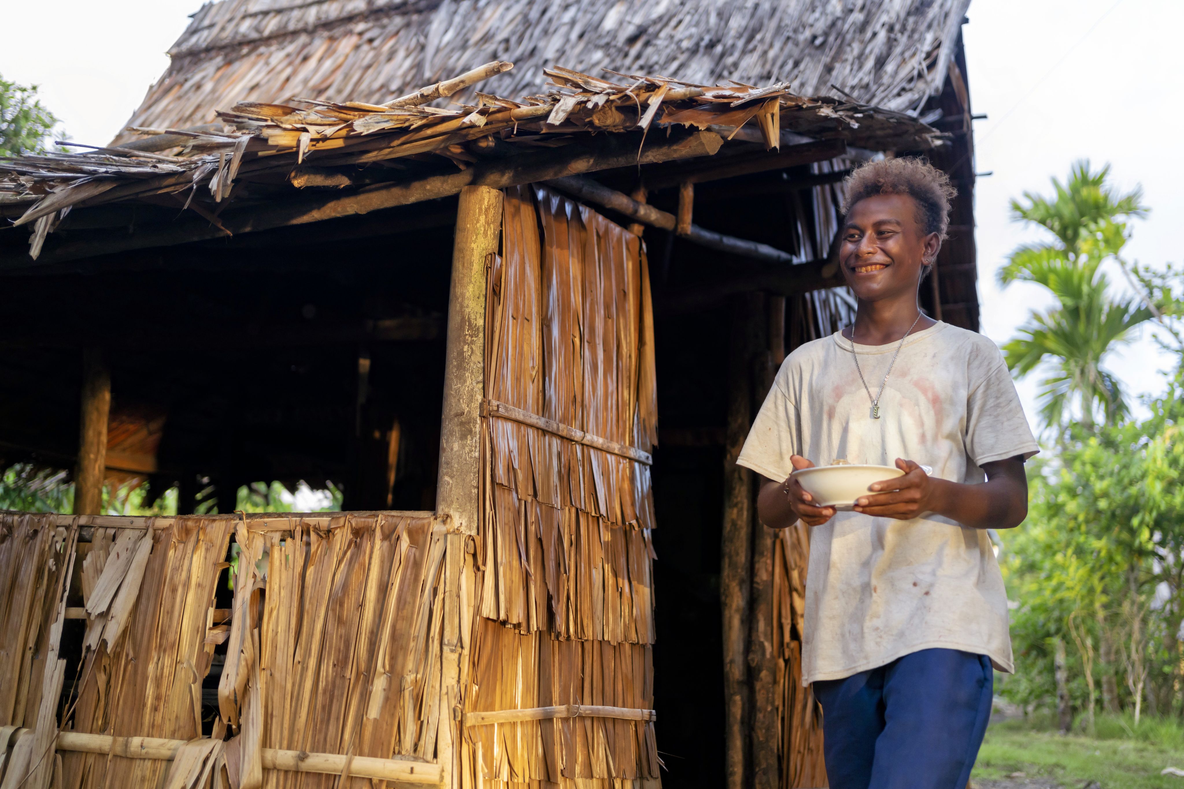 Junior, 16, carrying a bowl of food outside his home in a community affected by rising sea levels in Malaita Province, the Solomon Islands.