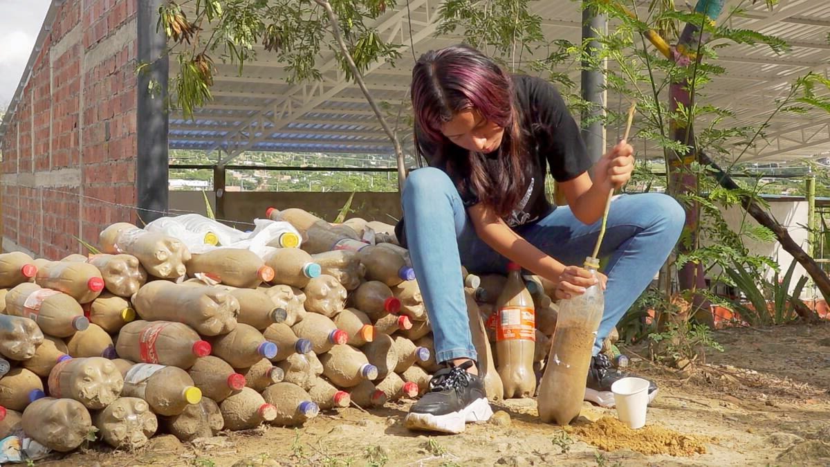 Oriana*, 15, fills a plastic bottle with sand so it can be recycled as a brick in Norte de Santander, Colombia