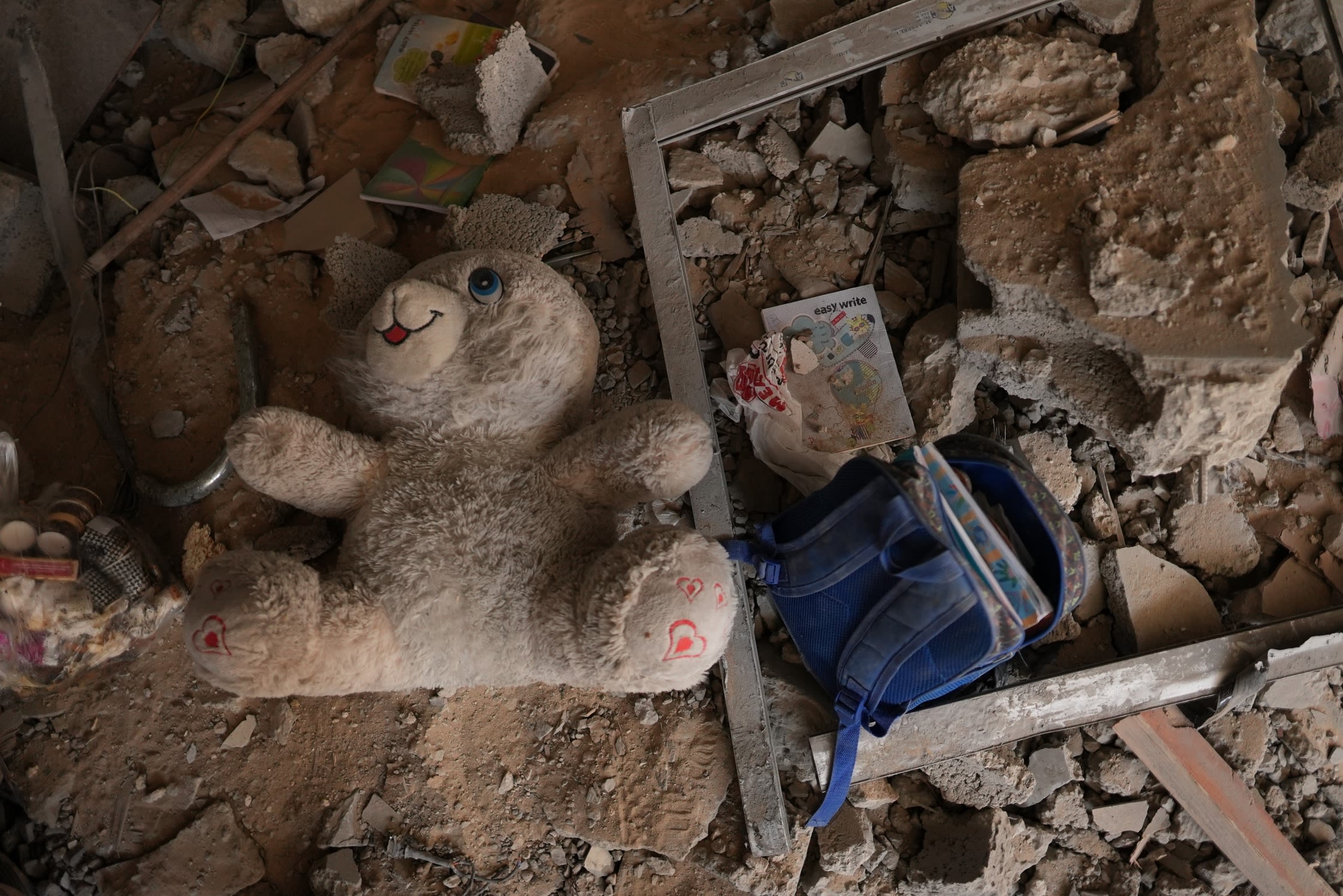 A child's school backpack and a doll amid rubble in Gaza