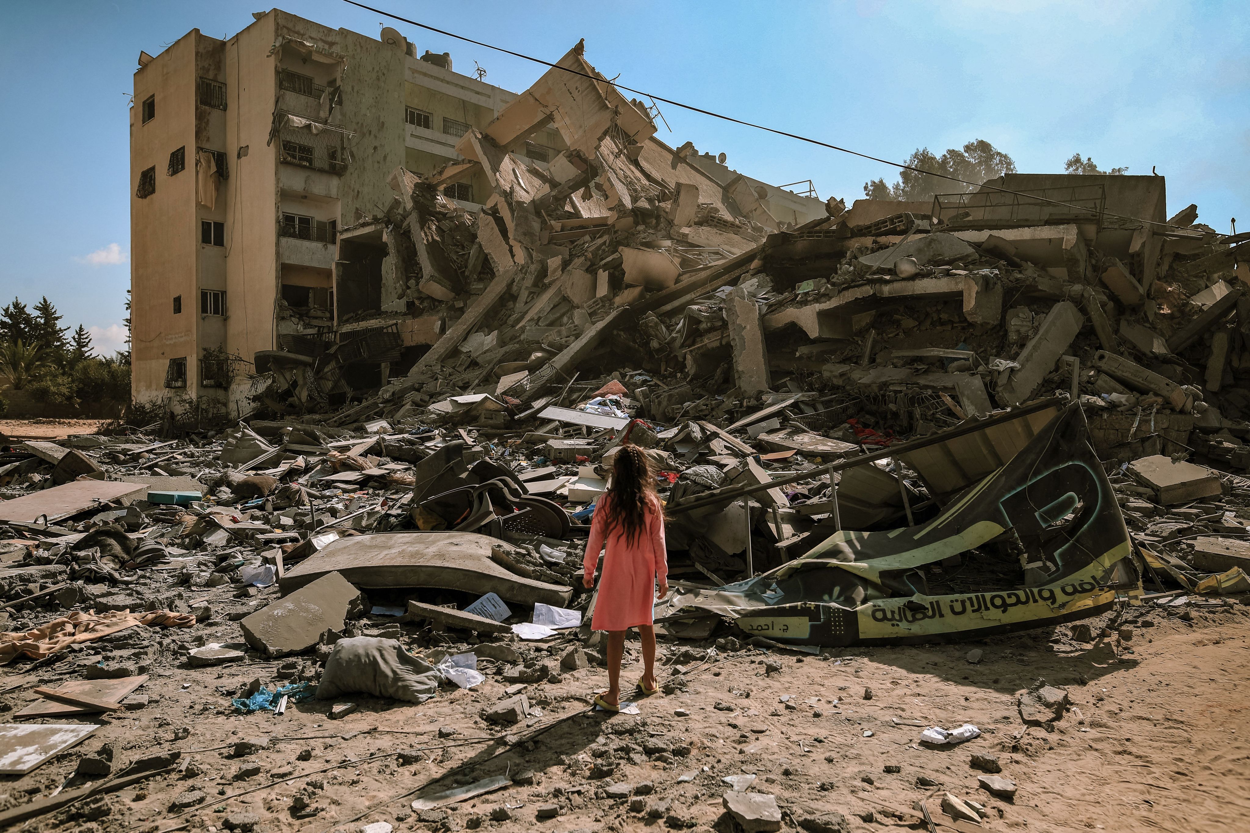 A young girl in Gaza stands amidst building rubble